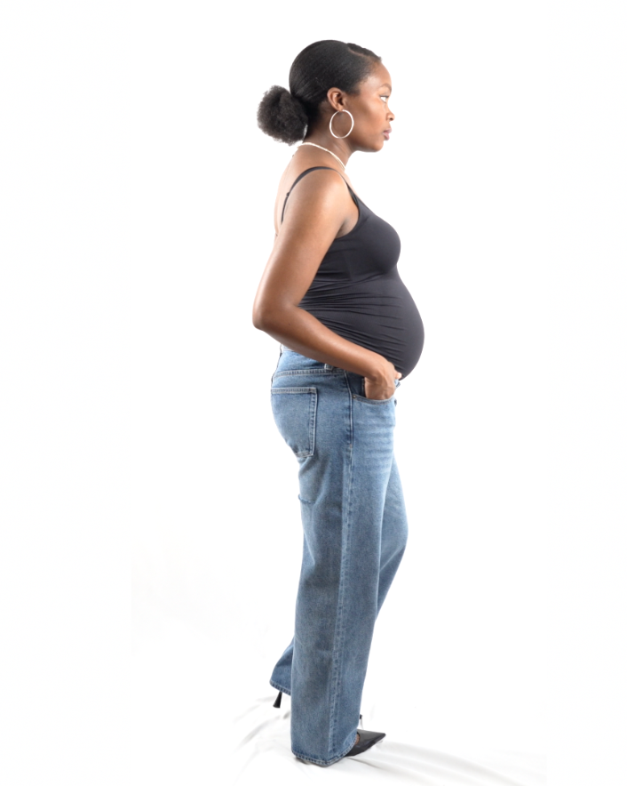 Side profile of The Joleen maternity denim showing the comfortable low-rise waist fit under the belly and the wide-leg silhouette with cut-out accents.
